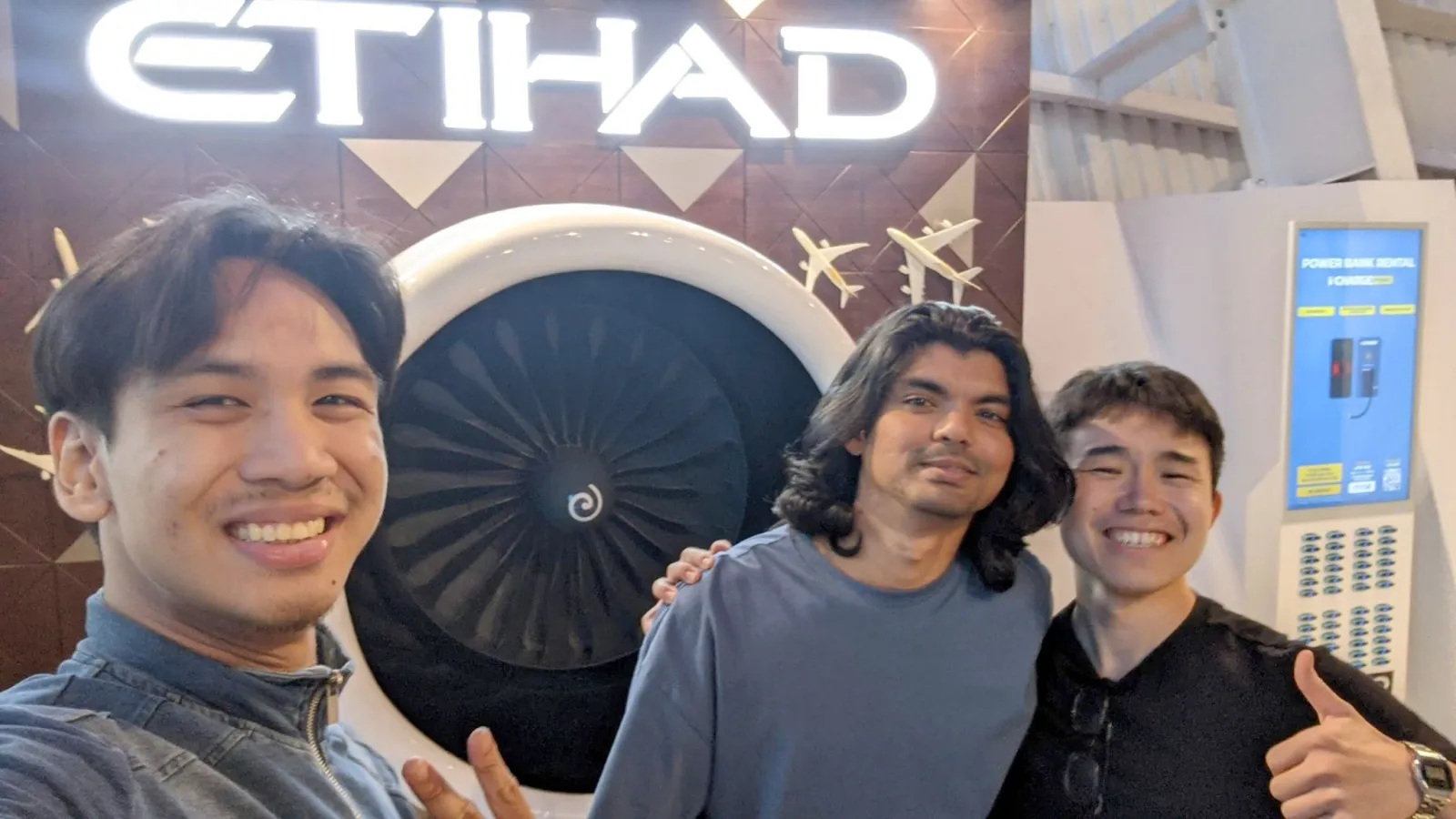 Three associates in front of an Etihad aircraft engine display
