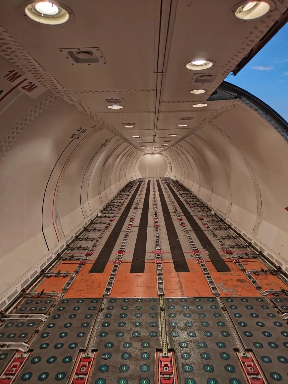 The empty main deck of a freighter, looking down the cargo floor towards the nose